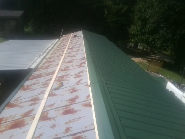 Old rusted panels beside newly installed green metal roofing — Wind Damage Roof Repair by Roofing Brothers in Sublime