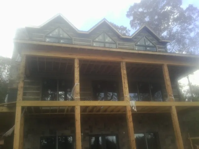 Dormers and porch framing on a large log home under construction — Roof Coating work by our crew in Sublime
