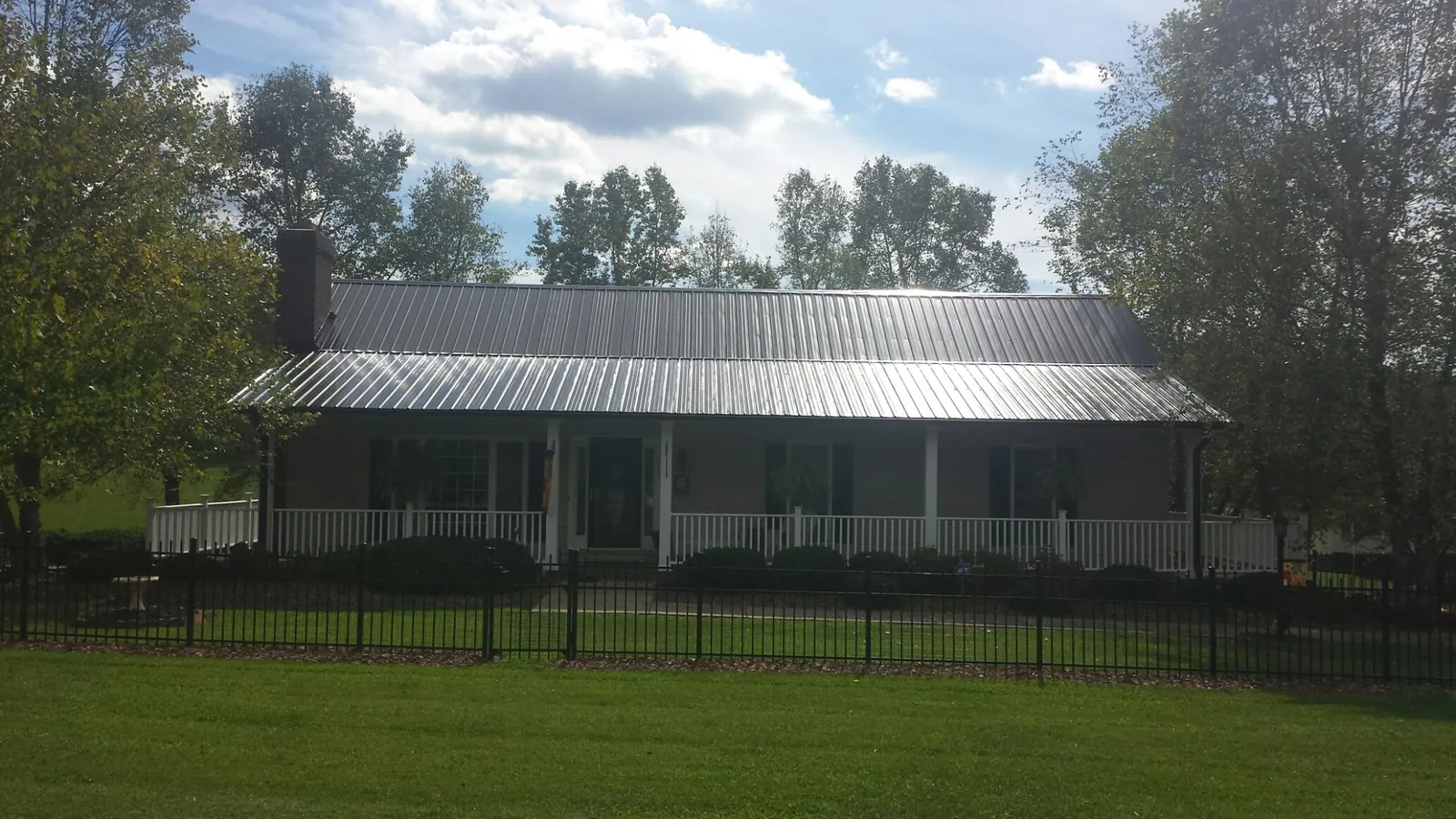 Gray metal roof on a brick ranch with a full width front porch — Gutter Guard Installation work by our crew in Sublime